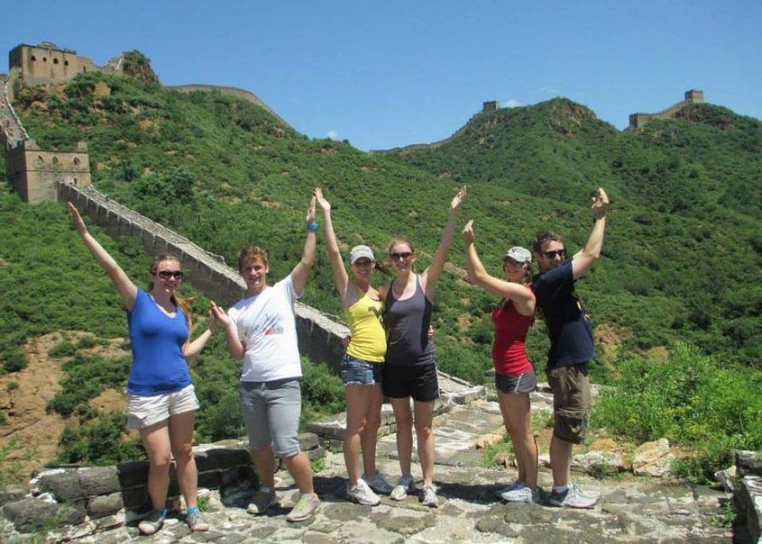Study abroad scholarship students posing for a picture at the Great Wall of China making 'WVU' with their arms