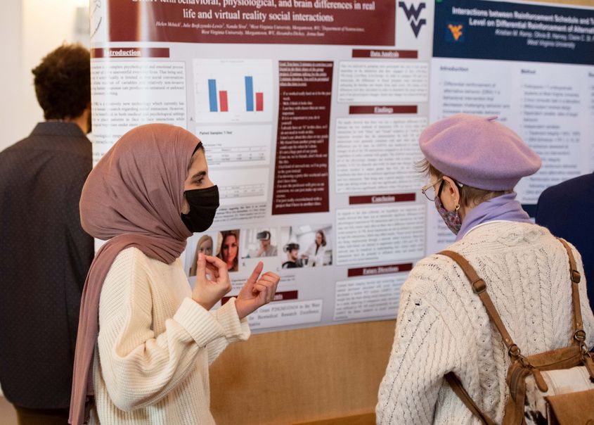 An honors student presenting research to another individual